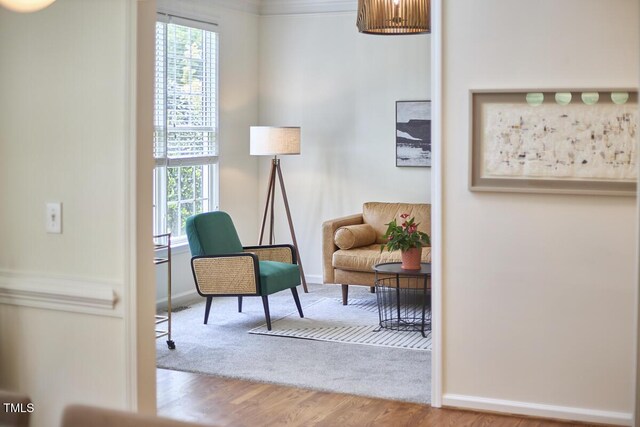 sitting room with baseboards, plenty of natural light, and wood finished floors