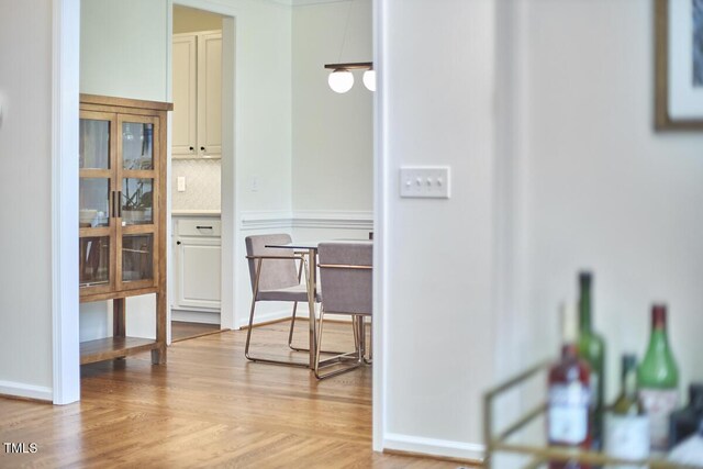 corridor with baseboards and light wood-style flooring