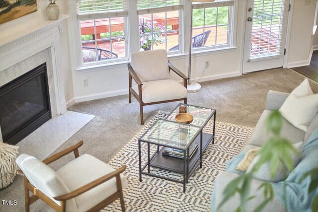 carpeted living area with plenty of natural light, baseboards, and a fireplace