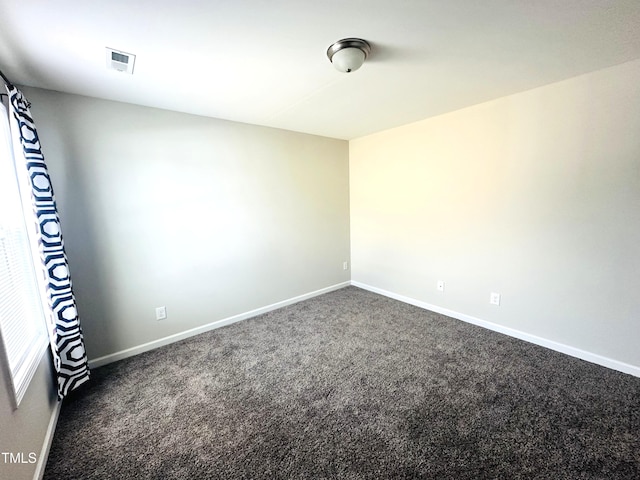 unfurnished room with baseboards, visible vents, and dark carpet