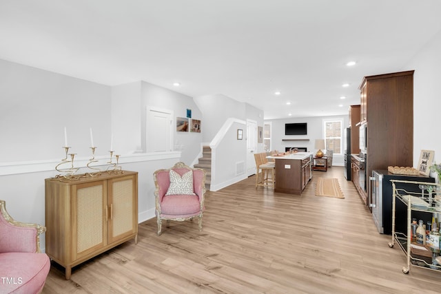 interior space featuring light wood-style floors, a fireplace, stairs, and visible vents