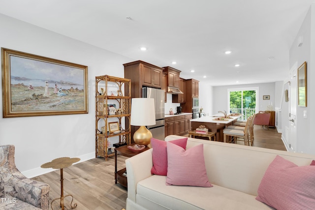 living area featuring baseboards, recessed lighting, and light wood-style flooring
