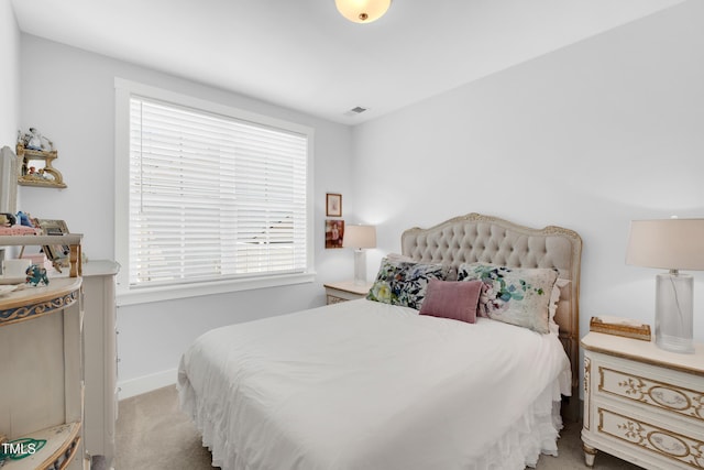 bedroom with baseboards, visible vents, and light carpet