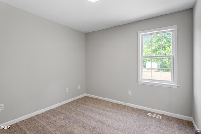 carpeted spare room featuring a healthy amount of sunlight, baseboards, and visible vents