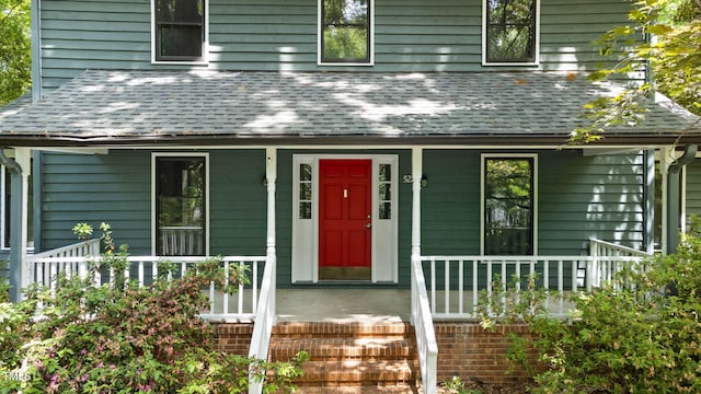 doorway to property with a porch and roof with shingles