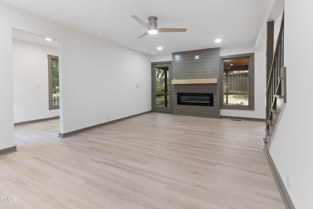 unfurnished living room with light wood-type flooring, ceiling fan, baseboards, recessed lighting, and a large fireplace