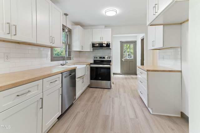 kitchen with appliances with stainless steel finishes, wooden counters, decorative backsplash, and light wood-style flooring
