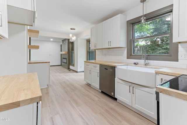 kitchen featuring wood counters, stainless steel dishwasher, tasteful backsplash, a sink, and decorative light fixtures