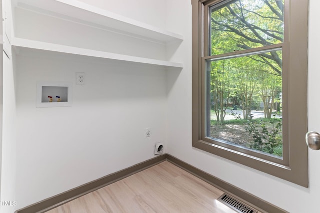 clothes washing area with hookup for a washing machine, hookup for an electric dryer, light wood-type flooring, and baseboards