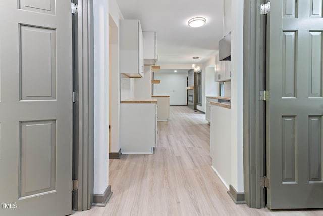 corridor with light wood finished floors and baseboards
