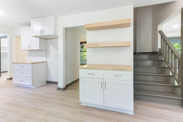 kitchen featuring open shelves, light wood finished floors, white cabinets, tasteful backsplash, and baseboards