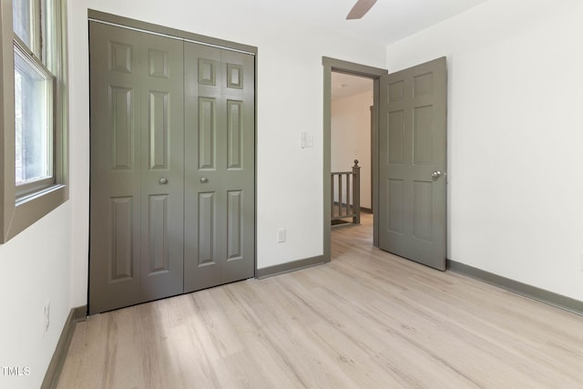unfurnished bedroom with light wood-type flooring, baseboards, a closet, and ceiling fan