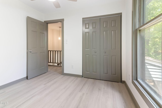 unfurnished bedroom with wood finished floors, baseboards, a closet, and a ceiling fan