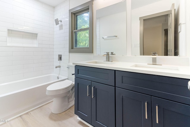 bathroom featuring toilet, wood finished floors, double vanity, and shower / bathtub combination
