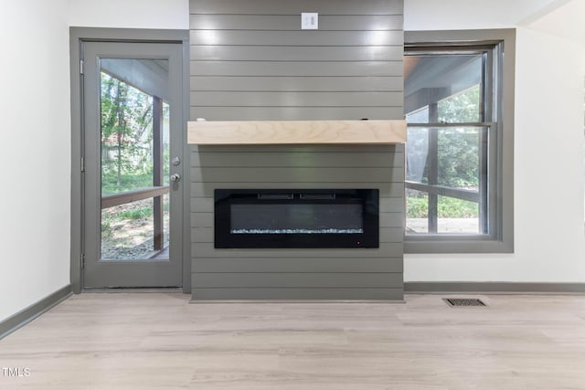 detailed view of a fireplace, wood finished floors, and baseboards