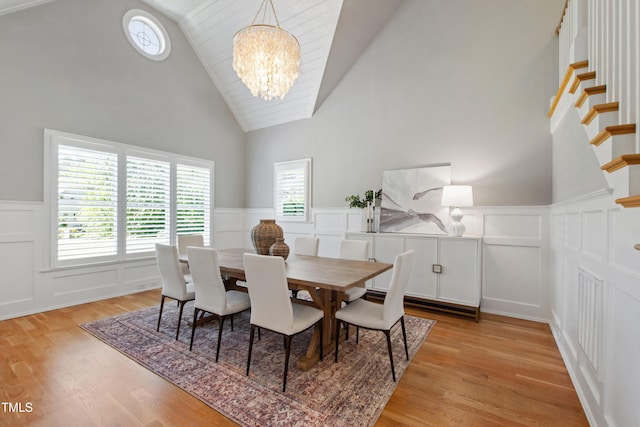6 Castlewood Dr, Durham, NC 27713 - dining area with a decorative wall, a chandelier, high vaulted ceiling, a wainscoted wall, and light wood-style floors