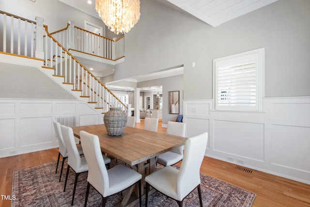 6 Castlewood Dr, Durham, NC 27713 - dining room featuring a decorative wall, wood finished floors, a chandelier, stairs, and a wainscoted wall