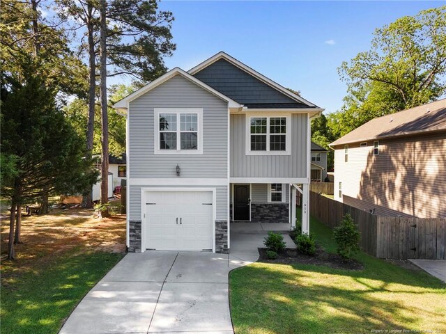 915 Carolina Ave, Fayetteville, NC 28301 - view of front facade with fence, an attached garage, a front lawn, stone siding, and board and batten siding