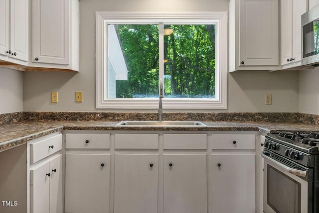 kitchen featuring stainless steel appliances, a wealth of natural light, a sink, and white cabinetry