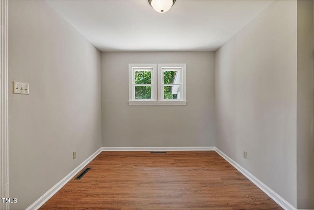 empty room featuring baseboards, visible vents, and wood finished floors