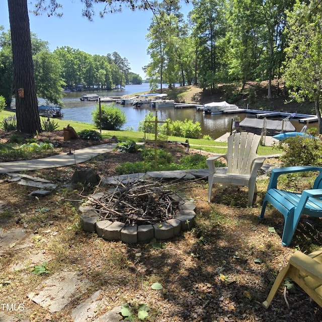 view of yard featuring a water view, an outdoor fire pit, and a boat dock
