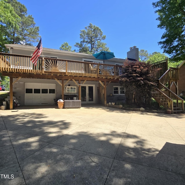view of front facade with a garage, a wooden deck, a chimney, french doors, and driveway