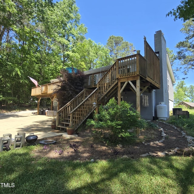 back of house with stairs, a wooden deck, and a chimney