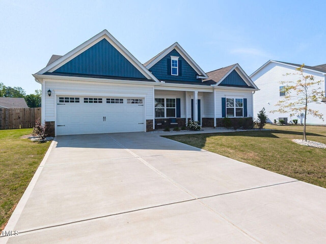 craftsman-style home with driveway, a front lawn, and stone siding