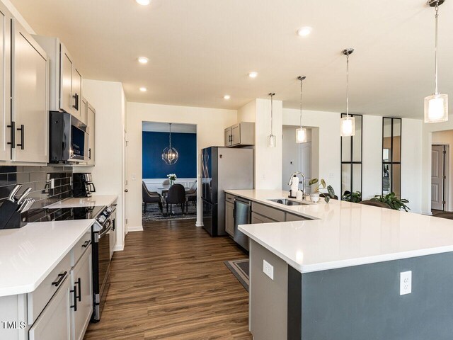 kitchen featuring dark wood-type flooring, a sink, appliances with stainless steel finishes, and light countertops