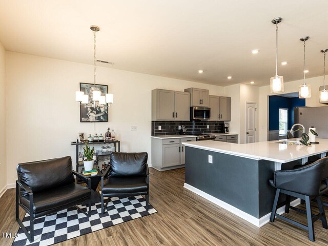 kitchen with gray cabinetry, appliances with stainless steel finishes, dark wood-style flooring, and light countertops