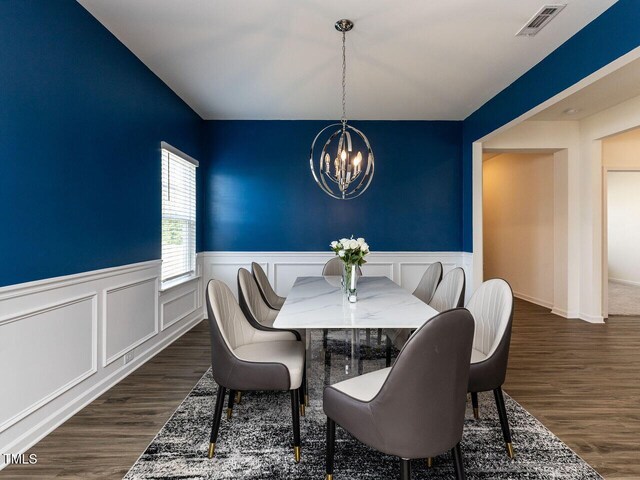 dining room with visible vents, wainscoting, dark wood finished floors, and a notable chandelier