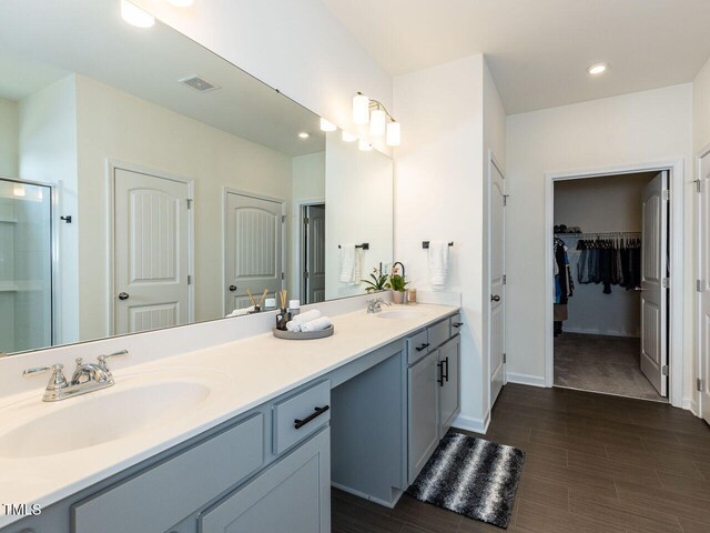 full bath with visible vents, double vanity, recessed lighting, a spacious closet, and a sink