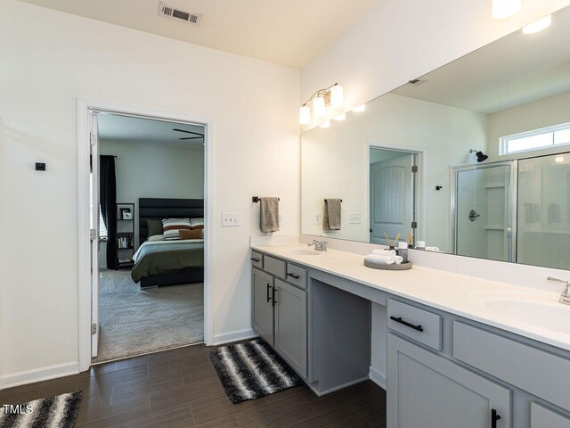 ensuite bathroom featuring a sink, a shower stall, ensuite bathroom, wood finished floors, and visible vents