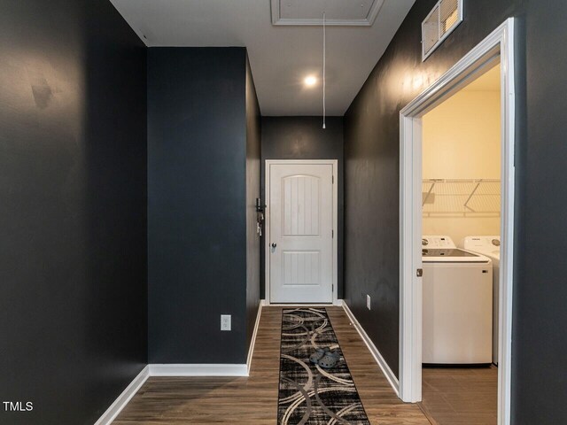 hall with attic access, visible vents, wood finished floors, baseboards, and washer and clothes dryer