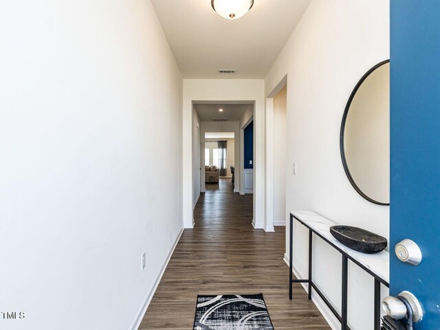 corridor with visible vents, baseboards, and wood finished floors