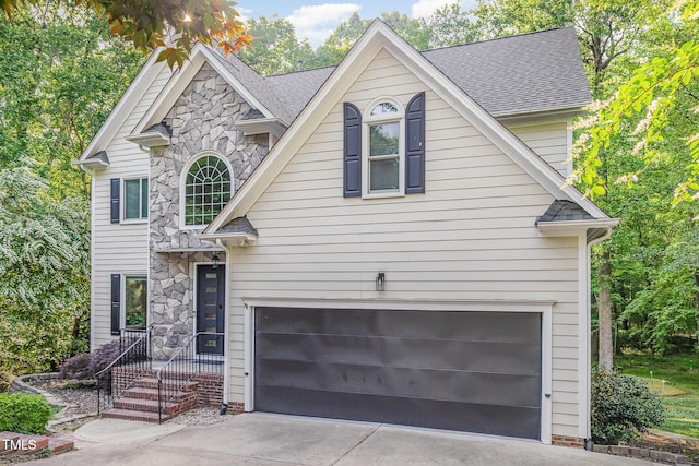 traditional-style home with an attached garage, a shingled roof, driveway, and stone siding
