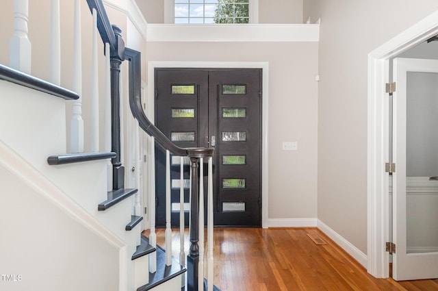 foyer entrance featuring stairway, baseboards, and wood finished floors