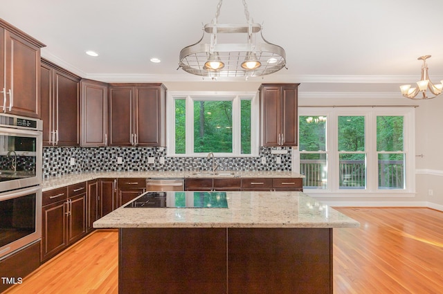 kitchen featuring ornamental molding, a chandelier, a sink, appliances with stainless steel finishes, and decorative light fixtures