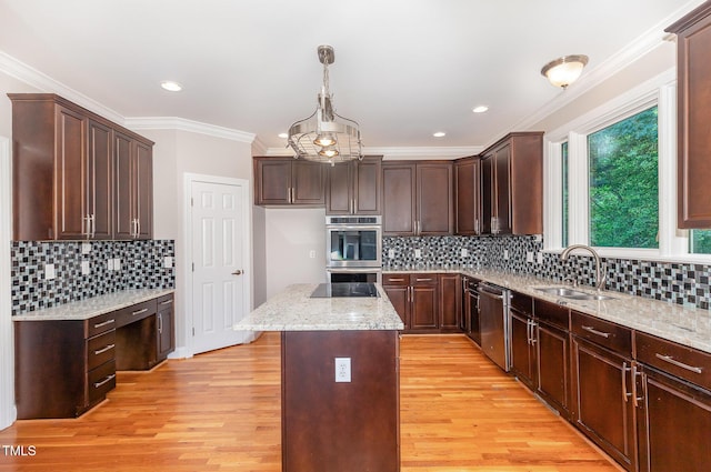 kitchen featuring a kitchen island, light stone countertops, light wood-type flooring, a sink, and appliances with stainless steel finishes