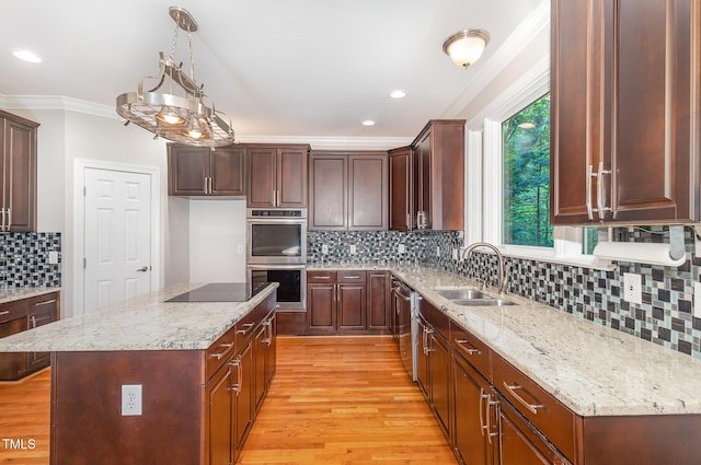 kitchen with ornamental molding, light wood-style floors, tasteful backsplash, a sink, and appliances with stainless steel finishes