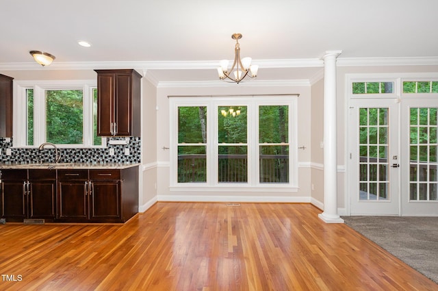 interior space featuring dark brown cabinetry, light countertops, tasteful backsplash, light wood-style flooring, and a notable chandelier