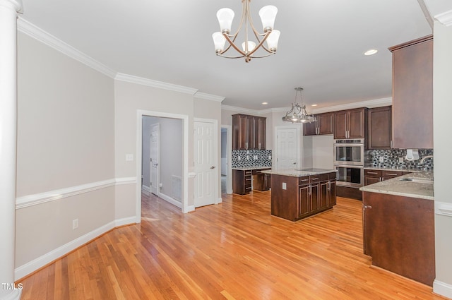 kitchen featuring backsplash, dark brown cabinets, double oven, a notable chandelier, and light wood-style flooring