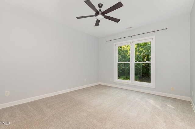 spare room featuring baseboards, a ceiling fan, visible vents, and light carpet