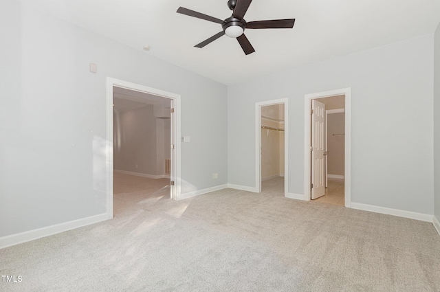 unfurnished bedroom featuring baseboards, light colored carpet, a walk in closet, and a closet