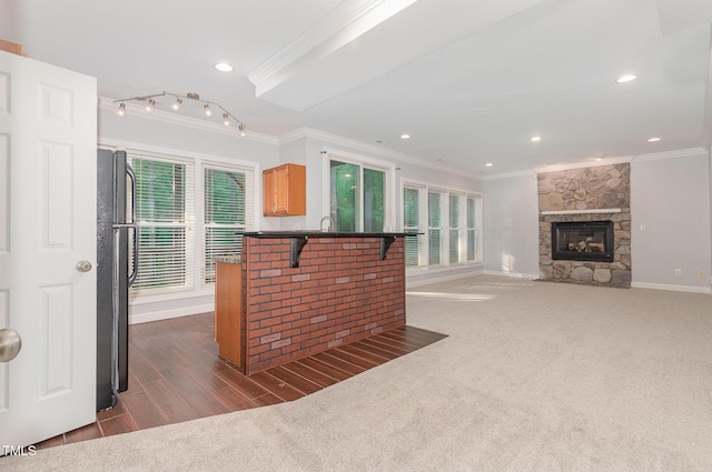 kitchen with a breakfast bar area, crown molding, a fireplace, baseboards, and freestanding refrigerator