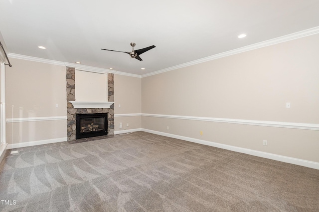 unfurnished living room featuring crown molding, ceiling fan, a stone fireplace, and carpet flooring