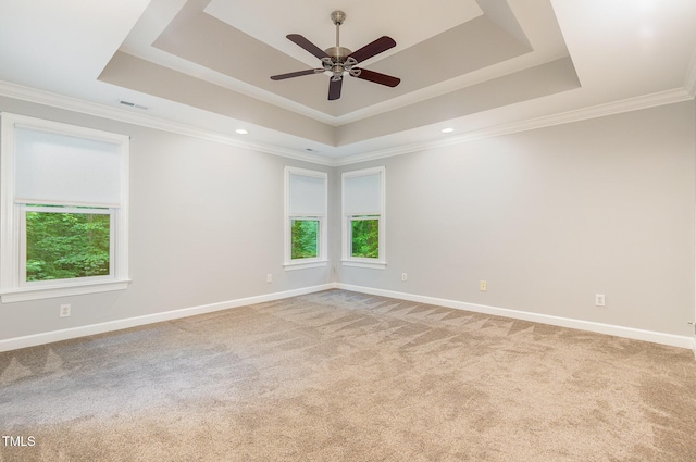 carpeted empty room with baseboards, a ceiling fan, a tray ceiling, and a wealth of natural light