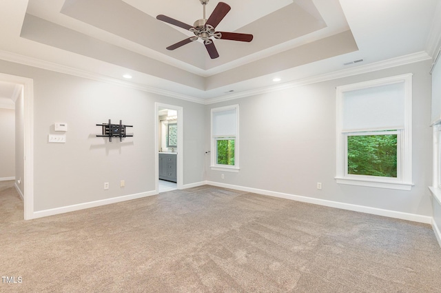 carpeted spare room featuring baseboards, a tray ceiling, ornamental molding, and ceiling fan