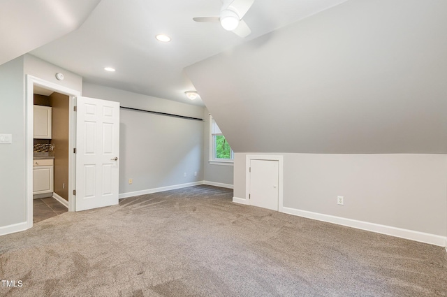 additional living space featuring vaulted ceiling, carpet floors, baseboards, and a ceiling fan