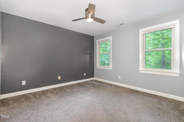 unfurnished room featuring visible vents, a ceiling fan, baseboards, and dark carpet